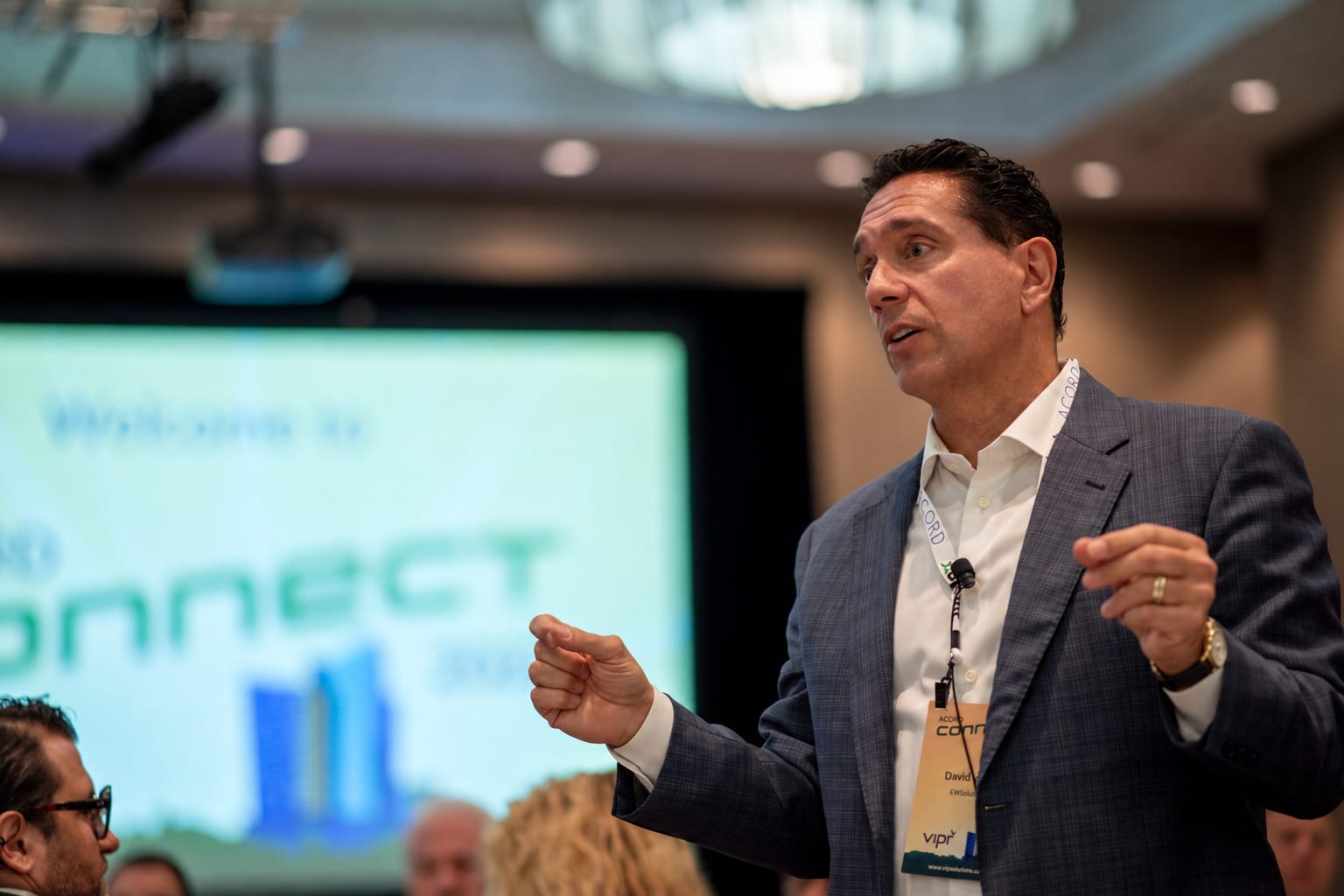 David Marco gesturing as he addresses a conference audience