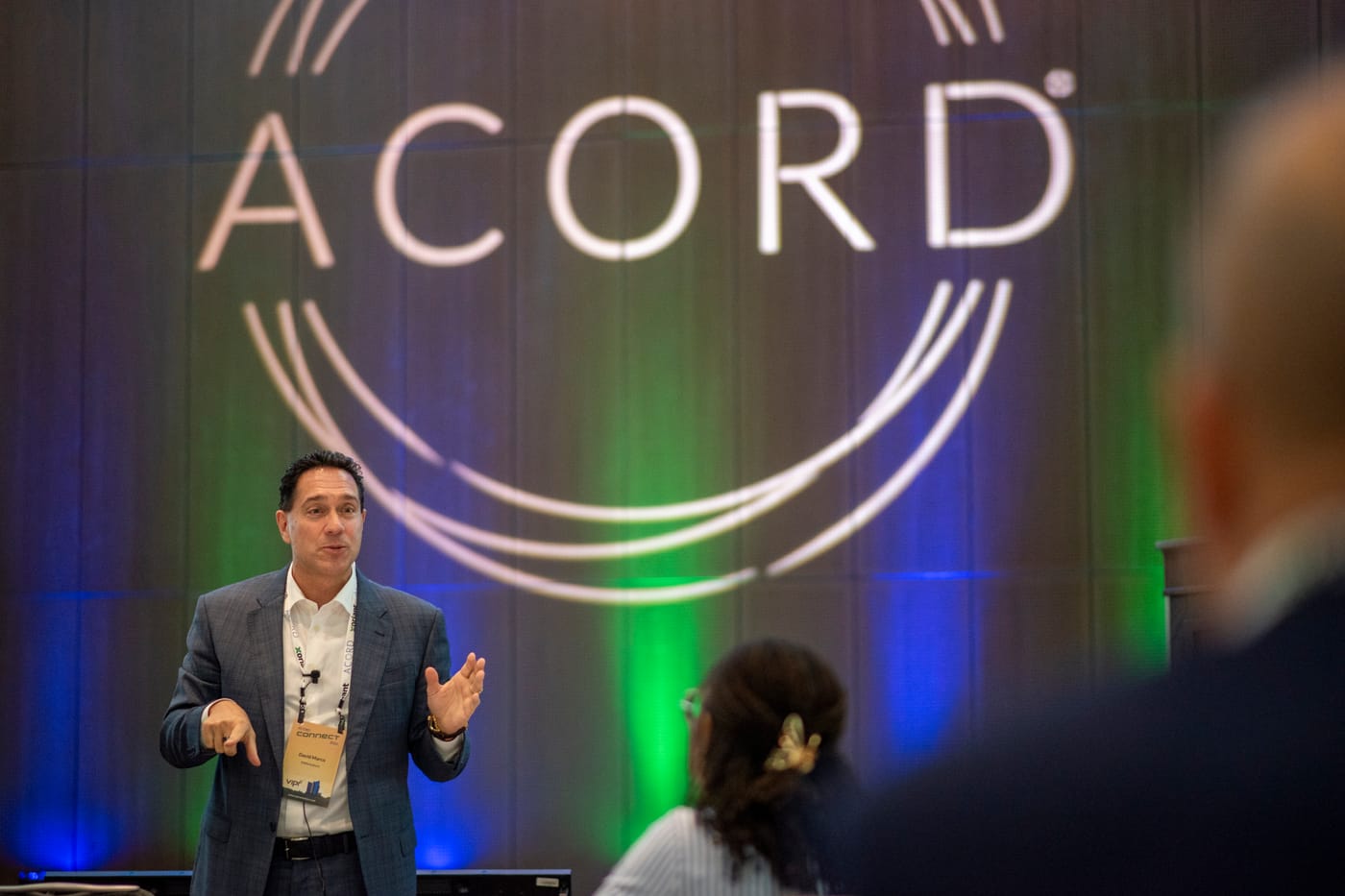 David Marco speaking from the stage to a seated audience